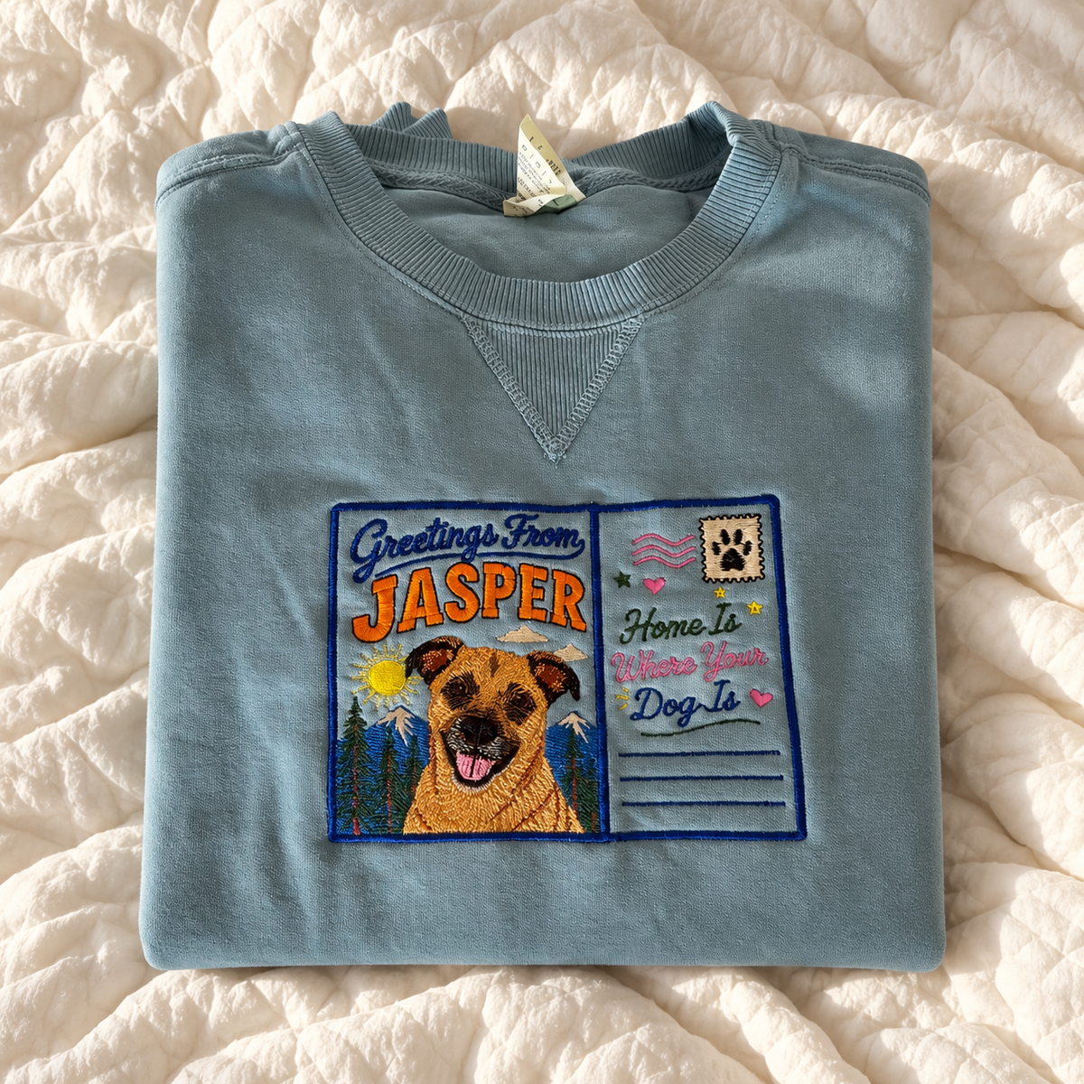 Custom embroidered pet portrait sweatshirt in Blue Jean with a Greetings From Jasper postcard design and dog portrait