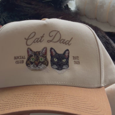 Video close-up of embroidered tabby and black cat portraits on a custom Cat Dad snapback hat